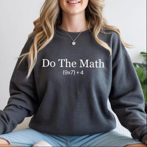 A woman wearing a gray sweatshirt with the text "Do The Math" printed on it.