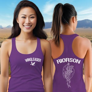A woman wearing a purple tank top with the text "WINGLEADER" and a dragon design on the front, standing in front of a desert landscape with mountains in the background.