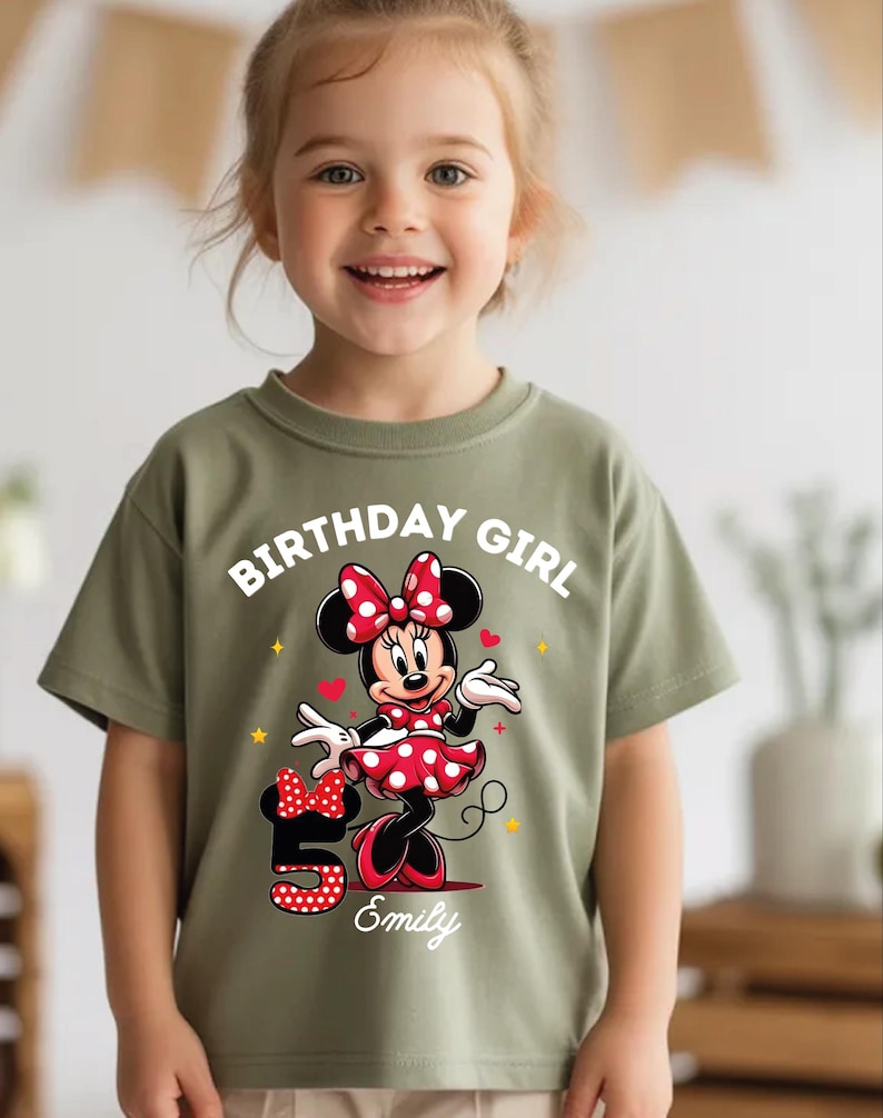 A young girl wearing a green t-shirt with a Minnie Mouse graphic and the text "Birthday Girl Emily" printed on it.