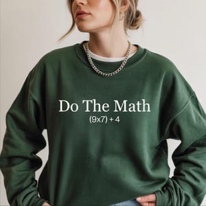 A woman wearing a green sweatshirt with the text "Do The Math" printed on it.