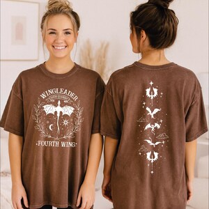 A woman wearing a brown t-shirt with a graphic design on the front and back.