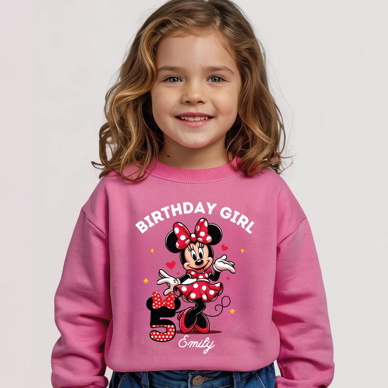 A young girl wearing a pink sweatshirt with a Minnie Mouse graphic and the text "Birthday Girl" printed on it.