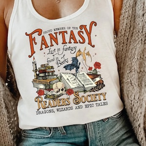 May include: White tank top with a fantasy-themed graphic. The design features the word "FANTASY" in orange, along with illustrations of books, dragons, roses, and the text "Proud Member of the Fantasy Readers Society".