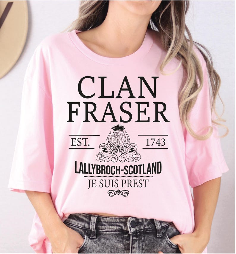 A woman wearing a pink t-shirt with text and graphics printed on it.