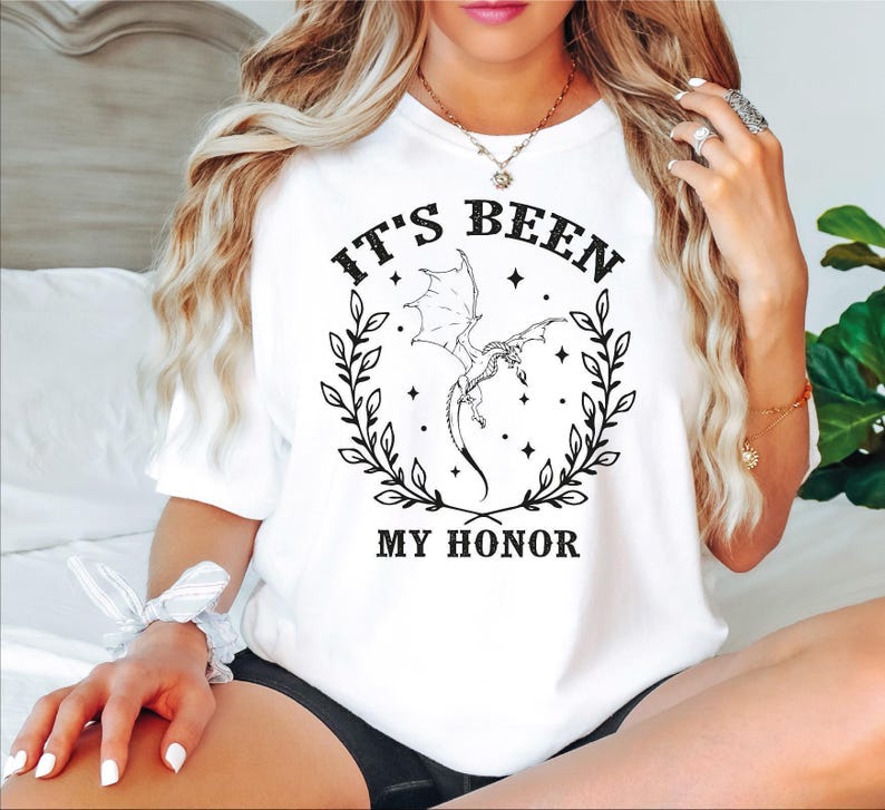 a woman sitting on a bed wearing a t - shirt that says it's