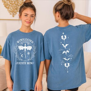 A woman wearing a blue t-shirt with a graphic design on the front and back.