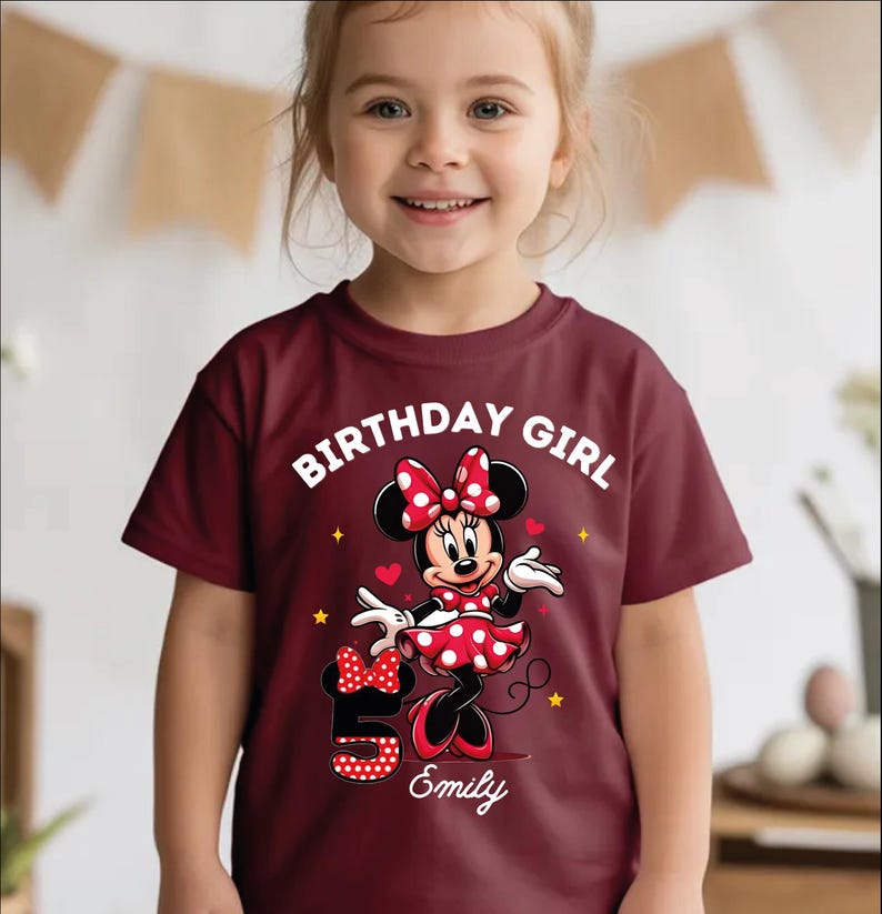 A young girl wearing a red t-shirt with a Minnie Mouse design and the text "Birthday Girl Emily" printed on it.