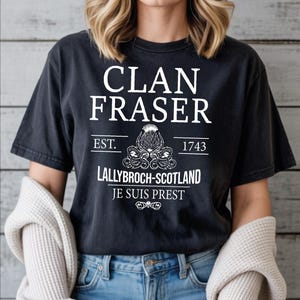 A woman wearing a black t-shirt with white text and graphics printed on it.