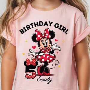 A young girl wearing a pink t-shirt with a Minnie Mouse design and the text "Birthday Girl Emily" printed on it.