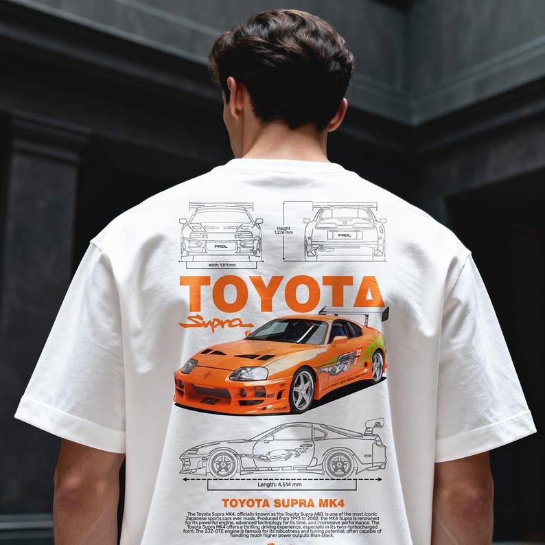 May include: White t-shirt featuring an orange Toyota Supra MK4 graphic. The design includes technical drawings, the Toyota logo, and the word "Supra." The car graphic is detailed with a spoiler and racing stripes.