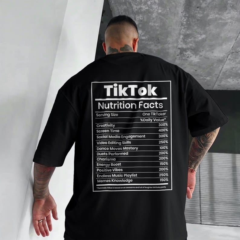 May include: Black oversized t-shirt with a white graphic on the back that reads "TikTok Nutrition Facts." The graphic lists percentages for creativity, screen time, social media engagement, and other social media-related activities.