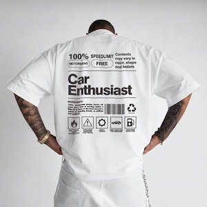 May include: White short-sleeved t-shirt with the text "100% SPEEDLIMIT FREE Car Enthusiast" in black. The shirt features a graphic design with icons and text, including "MOTORHEAD" and "INGREDIENTS".
