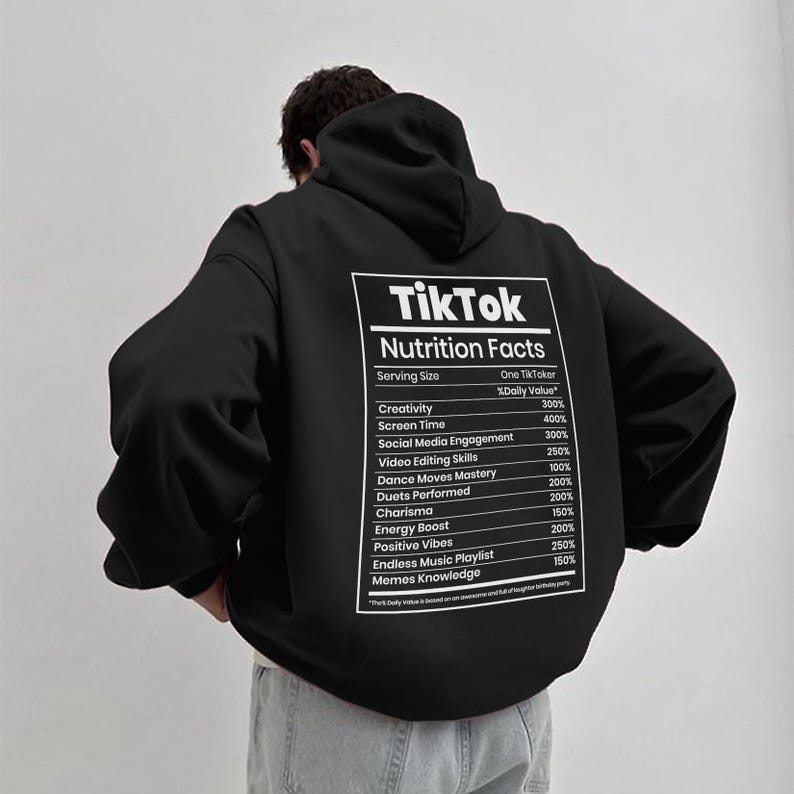 May include: Black hoodie with a white graphic on the back that reads "TikTok Nutrition Facts." The graphic lists values for creativity, screen time, social media engagement, and other categories. The hoodie has a hood and long sleeves.