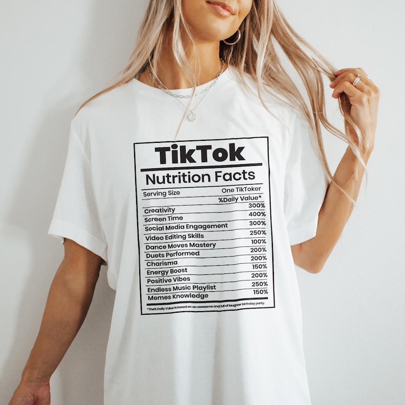 May include: White t-shirt with a black graphic resembling a nutrition facts label. The label reads "TikTok Nutrition Facts" and lists percentages for creativity, screen time, and other social media-related metrics.