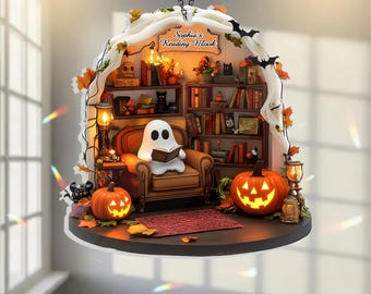 May include: A hanging ornament featuring a miniature reading nook with a white ghost sitting in a brown armchair reading a book. The scene includes bookshelves, two glowing jack-o'-lanterns, and a sign that reads Sophia's Reading Nook.