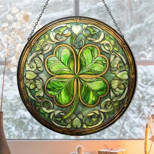 May include: A round stained glass window hanging with a four-leaf clover design in green and gold tones. The clover is surrounded by a decorative border of gold and green.