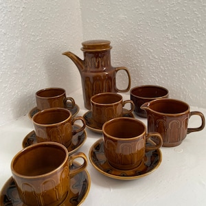 May include: A brown and black patterned tea set with a teapot, creamer, sugar bowl, and six cups and saucers.