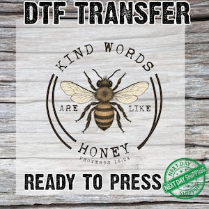 May include: DTF transfer with a detailed illustration of a bee, surrounded by the words "Kind Words Are Like Honey" and "Ready to Press." The design includes the text "Proverbs 16:24" and a "Next Day Shipping" seal.