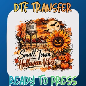 May include: A DTF transfer sheet featuring a graphic with the text DTF TRANSFER and READY TO PRESS. The design shows a water tower labeled SMALL TOWN, a full moon with bats, a sunflower with a jack-o'-lantern face, and pumpkins with the text Small Town Halloween Vibes.