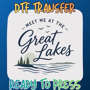May include: A DTF transfer sheet featuring the text "MEET ME AT THE GREAT LAKES" in dark blue script and sans-serif font. The design includes a graphic of a lake, pine trees, a sun, and birds. The words "DTF TRANSFER" and "READY TO PRESS" appear.