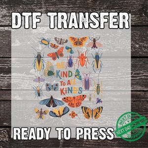 May include: DTF transfer featuring a collection of colorful butterflies and insects. The design includes the text "Be Kind To All Kinds" and "Ready To Press". The image has a rustic, wood-grain background.