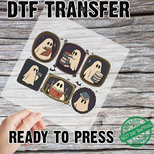 May include: DTF TRANSFER with the text "READY TO PRESS". The image shows a sheet with six framed ghost illustrations, each holding a book. The frames are various shapes and colours, with a spooky theme. The ghosts are white with black eyes.