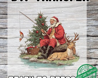 May include: DTF transfer featuring Santa Claus fishing next to a Christmas tree and a reindeer. Santa is wearing a red suit and hat, sitting on a log. The text "READY TO PRESS" is at the bottom.