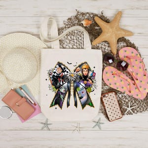 May include: A cream-colored tote bag featuring a bow-shaped design with images of Disney villains. The word "Villains" is printed in the center. The bag is surrounded by a straw hat, sunglasses, starfish, and pink flip-flops.
