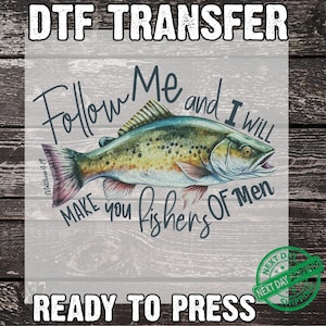 May include: DTF transfer featuring a detailed illustration of a fish with text that reads "Follow Me and I Will Make you fishers Of Men" and "Ready to Press". The fish is in shades of green, yellow, and pink.