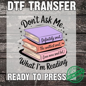 May include: DTF transfer design featuring a stack of three books with the text "Don't Ask Me What I'm Reading." The books are labeled "Definitely smut," "The smuttiest smut," and "Even more smut lol." The design includes stars and the words "READY TO PRESS."