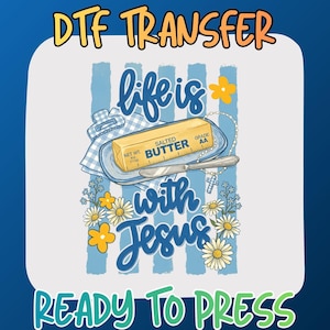May include: A DTF transfer graphic featuring a stick of salted butter on a dish with a knife, a rosary, and daisies. The text reads "life is with Jesus" in blue script. The background has light blue vertical stripes and yellow flowers.