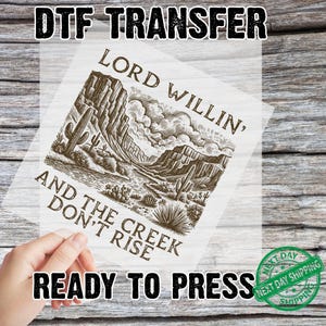 May include: A DTF transfer with a sepia-toned desert landscape design featuring cacti, mountains, and the text "LORD WILLIN', AND THE CREEK DON'T RISE." The words "READY TO PRESS" are also visible.