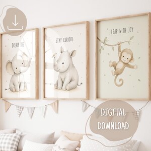 Könnte beinhalten: Drei gerahmte Wandbilder mit Aquarellillustrationen eines Babyelefanten mit dem Text DREAM BIG, eines Nashorns mit dem Text STAY CURIOUS und eines an einem Ast hängenden Affen mit dem Text LEAP WITH JOY, alle in hellen Holzrahmen.