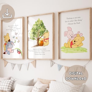 May include: Three framed Winnie the Pooh art prints with quotes. The prints feature illustrations of Winnie the Pooh, Piglet, and Eeyore. The prints are in wooden frames and are displayed above a row of pillows and a banner.