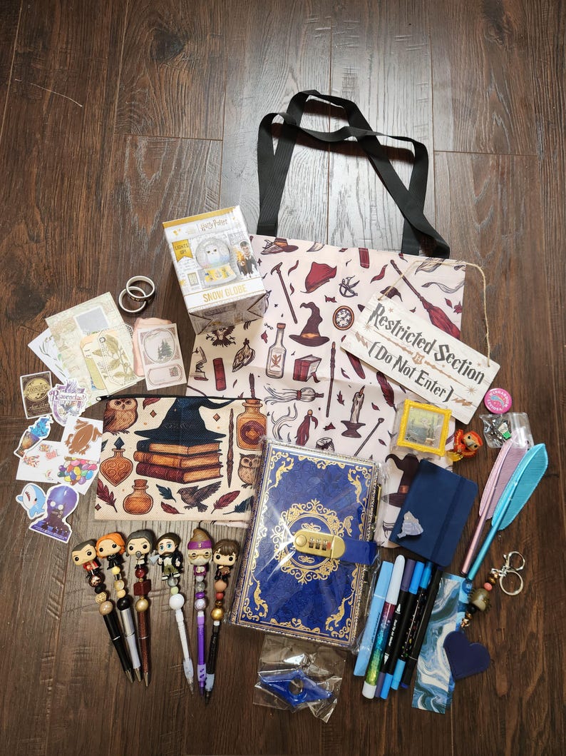 May include: A collection of Harry Potter themed merchandise including a tote bag with a pattern of magical items, a blue lockable journal, a snow globe box, a wooden sign reading Restricted Section Do Not Enter, various pens with character toppers, stickers, and stationery.