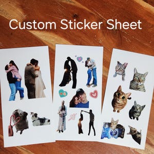 Può includere: Tre fogli di adesivi personalizzati con immagini di coppie, animali domestici e gatti. Il testo "Custom Sticker Sheet" è visualizzato in alto. Gli adesivi sono su una superficie di legno.
