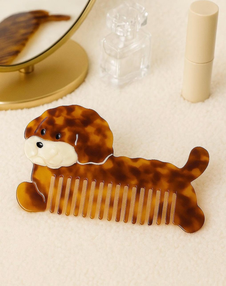 K&ouml;nnte beinhalten: Ein braun-beiger Kamm in Hundeform mit Schildpattmuster. Der Kamm hat ein wei&szlig;es Gesicht und liegt. Die Z&auml;hne des Kamms sind sichtbar. Der Kamm ist ein Sch&ouml;nheitsaccessoire.