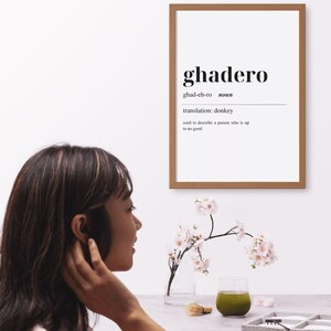 May include: A framed print with the word "ghadero" in a bold font, with the definition and translation below. A woman is seen in profile, with a glass of green liquid, a small brush, and a tray with a miniature zen garden.