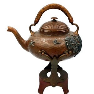 Könnte beinhalten: Eine weiße Keramik-Tasse mit schwarzem Henkel und dem Text "But First, Coffee" in fetter, schwarzer Schrift. Die Tasse steht vor einem verschwommenen Hintergrund. Die Tasse ist etwa 10 cm hoch.