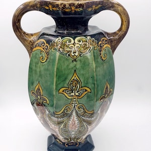 May include: A green and gold ceramic vase with intricate floral designs. The vase has two handles and a wide mouth.