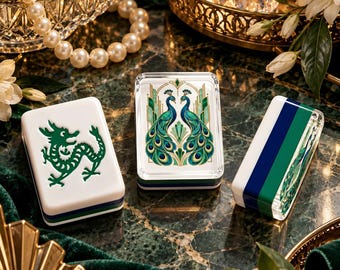 Può includere: Tre tessere rettangolari da mahjong con finitura lucida. Una tessera presenta l'illustrazione di un drago verde, un'altra mostra due pavoni simmetrici in blu e verde, e la terza presenta un motivo a strisce verticali blu navy, verde e bianco.