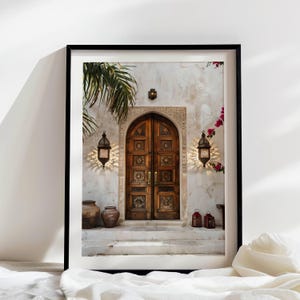 May include: A weathered wooden double door with intricate carvings, set in a white stucco wall with a palm tree and hanging lanterns. The door is framed by a stone archway and has a worn, rustic look.