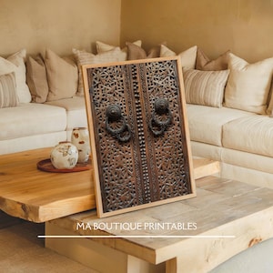 May include: A framed wooden print featuring a detailed carving of a door with ornate patterns and metal ring handles. The print is displayed on a wooden coffee table, with the text "MA BOUTIQUE PRINTABLES" at the bottom. The background includes a sofa and decorative vases.