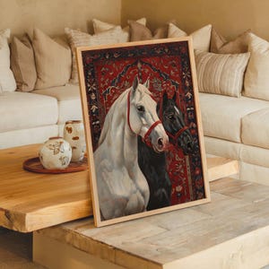 Puede incluir: Impresión artística enmarcada que presenta dos caballos, uno blanco y otro negro, sobre un fondo rojo estampado. Los caballos llevan bridas rojas. La obra se muestra en un marco de madera clara, ideal para la decoración del hogar.