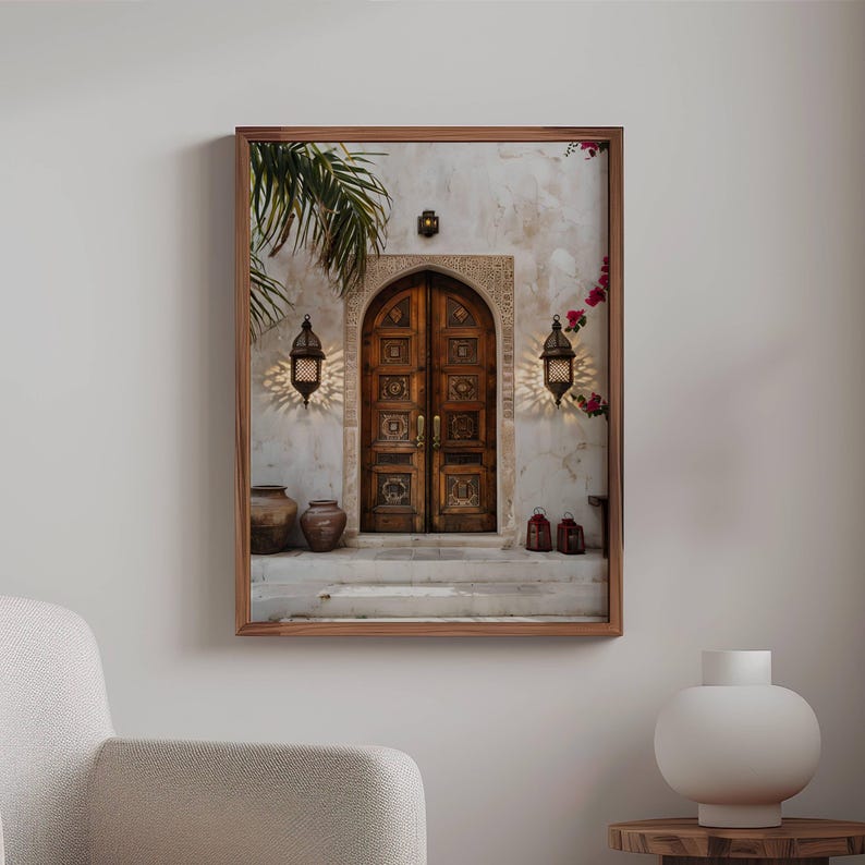 May include: A photograph of a wooden door with intricate carvings, framed by a white wall with a palm tree in the background. Two lanterns hang on either side of the door, and there are terracotta pots on the steps leading up to the door.