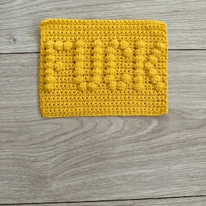 May include: A yellow crocheted dishcloth with a textured pattern.