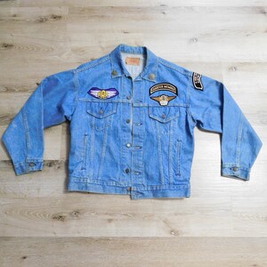 May include: A blue denim jacket with several patches, including a "HOG" patch, a "Charter Member" patch, and a "Harley Owners Group" patch.