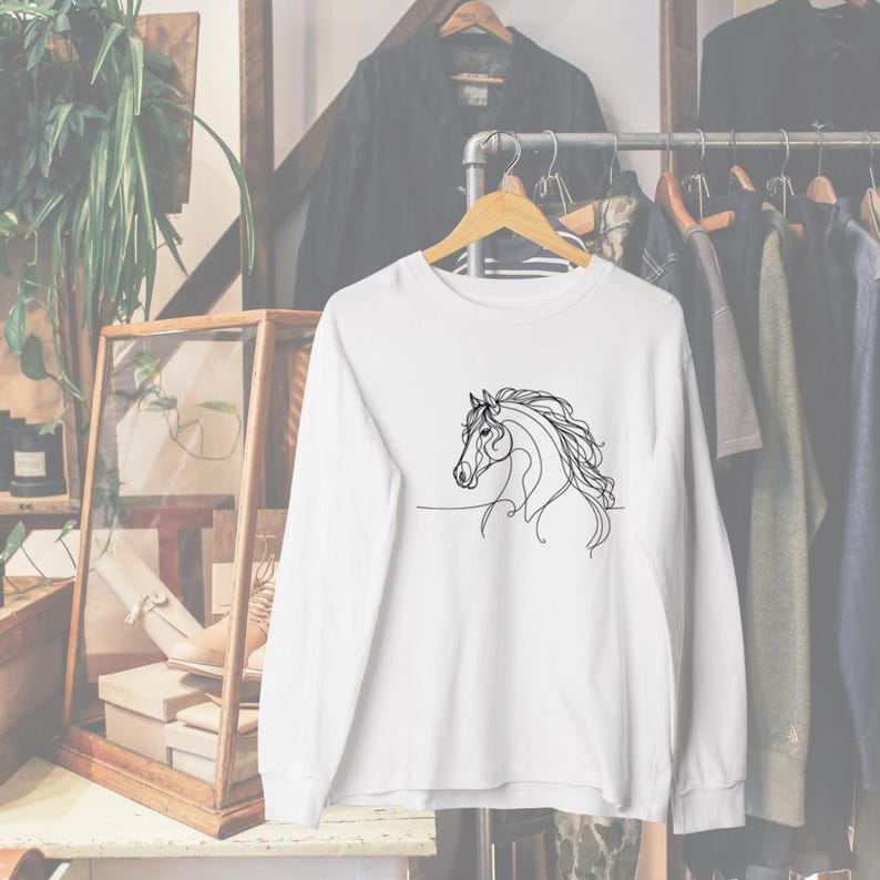 May include: White long-sleeved shirt with a black line drawing of a horse's head on the front.