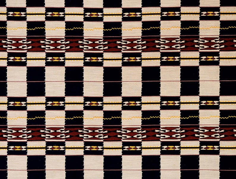 May include: A woven textile with a repeating pattern of large, alternating black and off-white squares. The design includes horizontal bands with geometric shapes in brown, yellow, and black, creating a bold, graphic look.