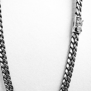 Puede incluir: Un collar de cadena curb plateado con cierre.